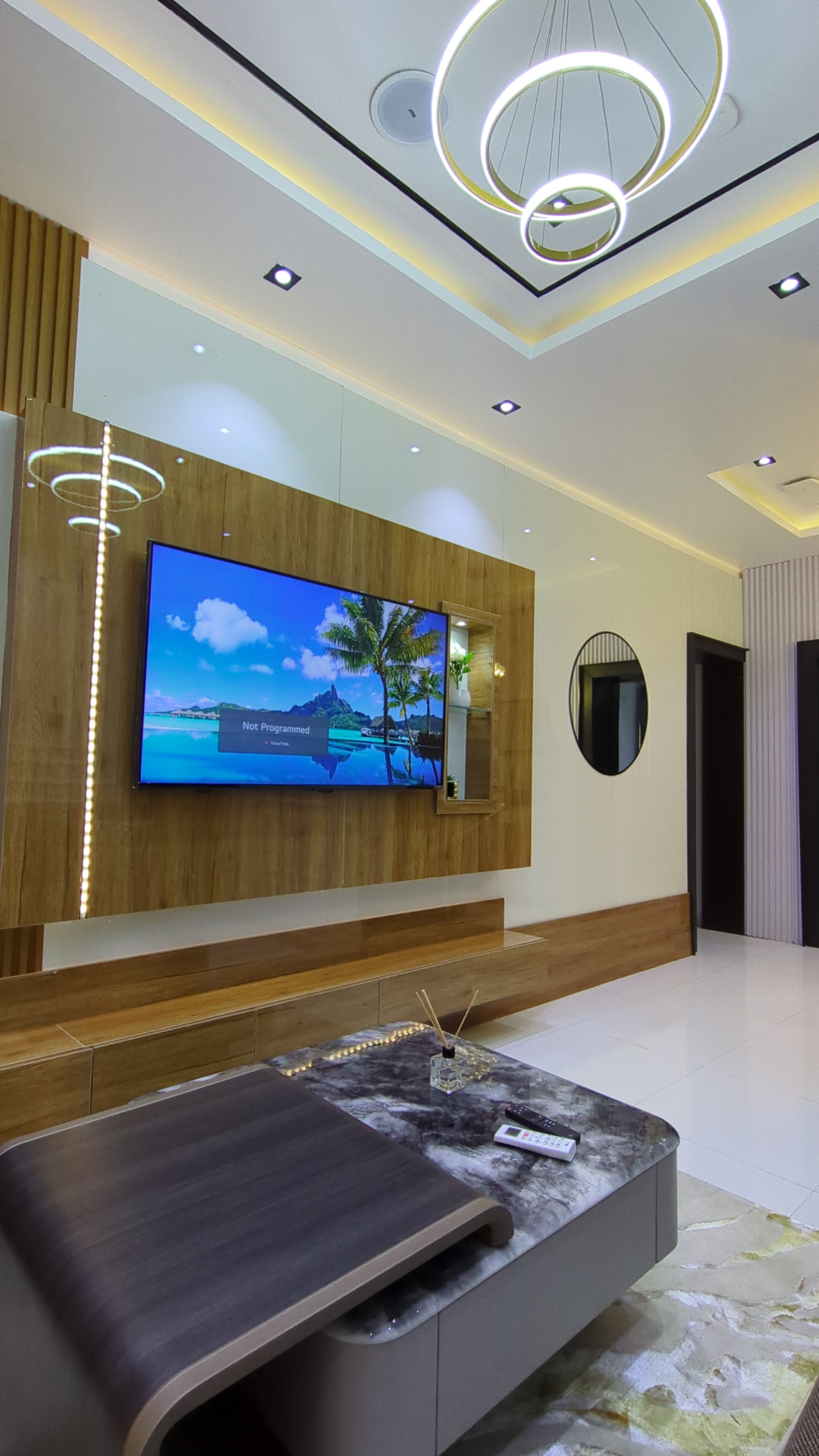 Living lounge with wall-mounted smart TV and ring chandelier
