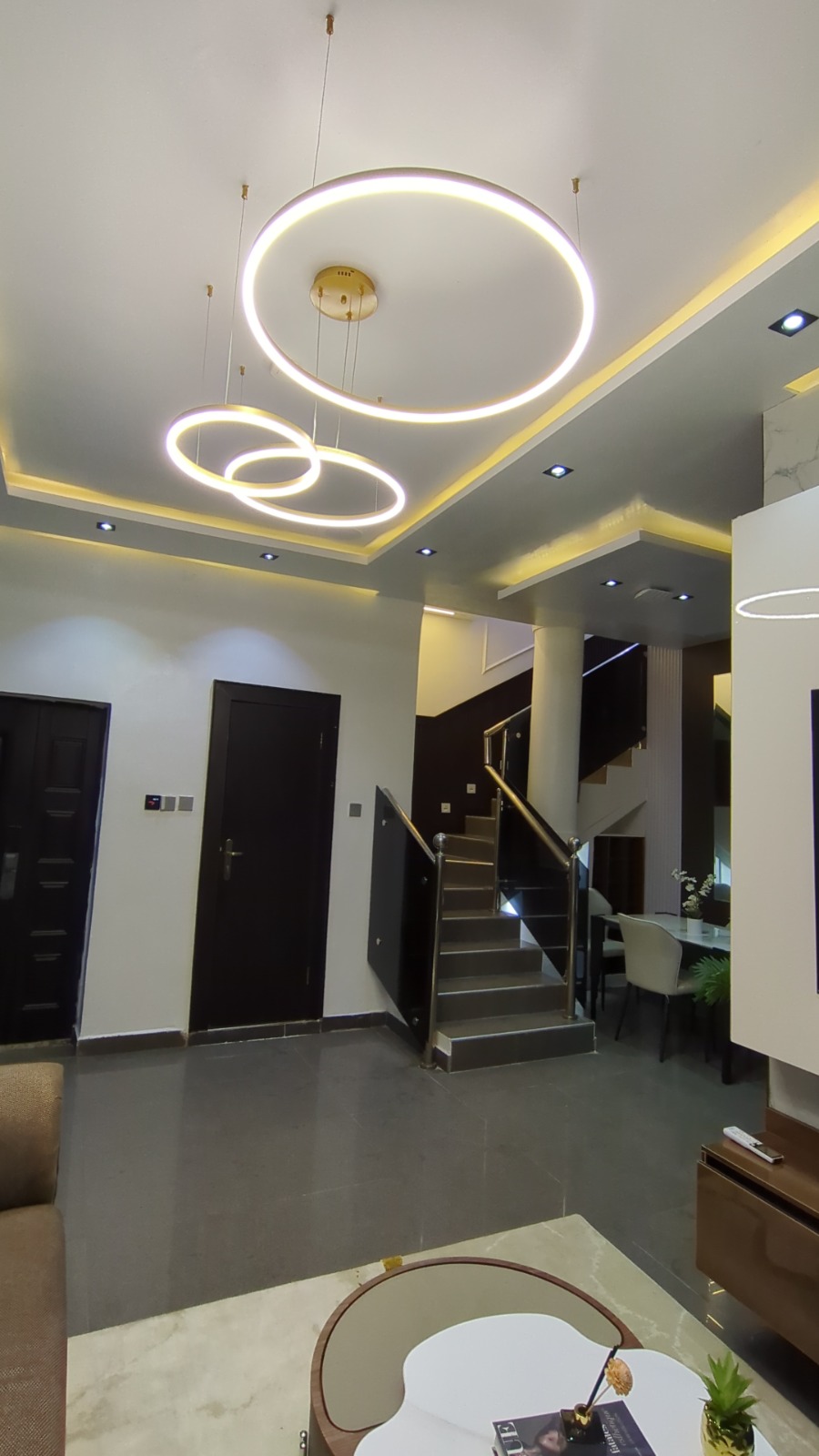 Foyer with sculptural ring pendant lighting and staircase
